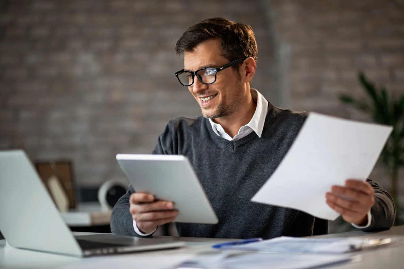Especialista revisando relatórios financeiros em tablet e no laptop